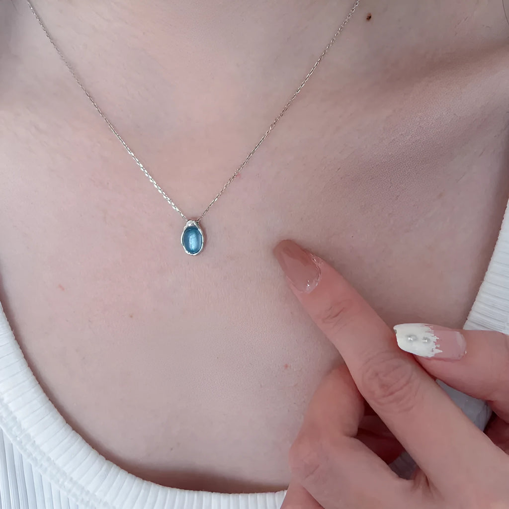Navy blue water drop geometric pendant necklace with cross chain design on white background