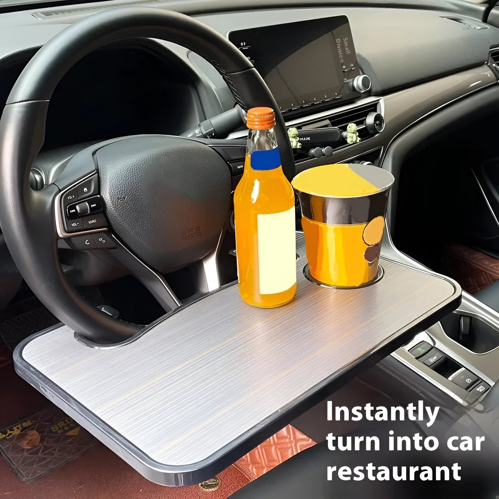 Black foldable car steering wheel laptop stand with integrated cup holder on a car seat.