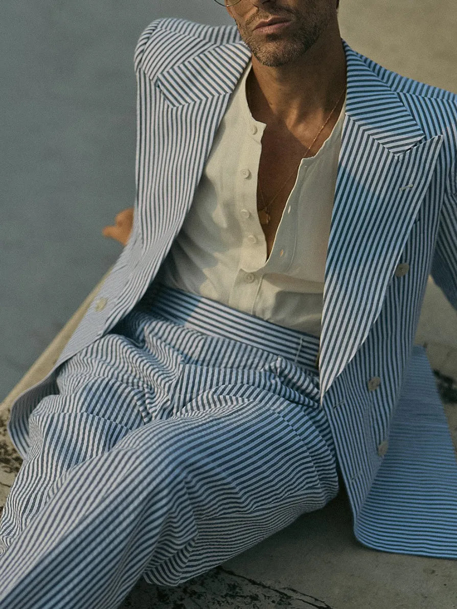 Blue and white striped polyester blazer and trousers suit set laid flat.