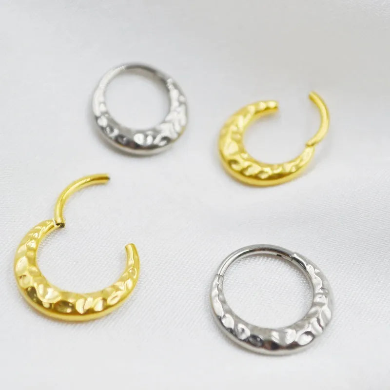Close-up of a carved concave-convex titanium nose ring in gold finish, showing textured surface.