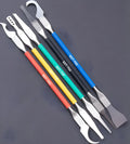 Five stainless steel plastic removal pry tools for electronics disassembly on a work surface.