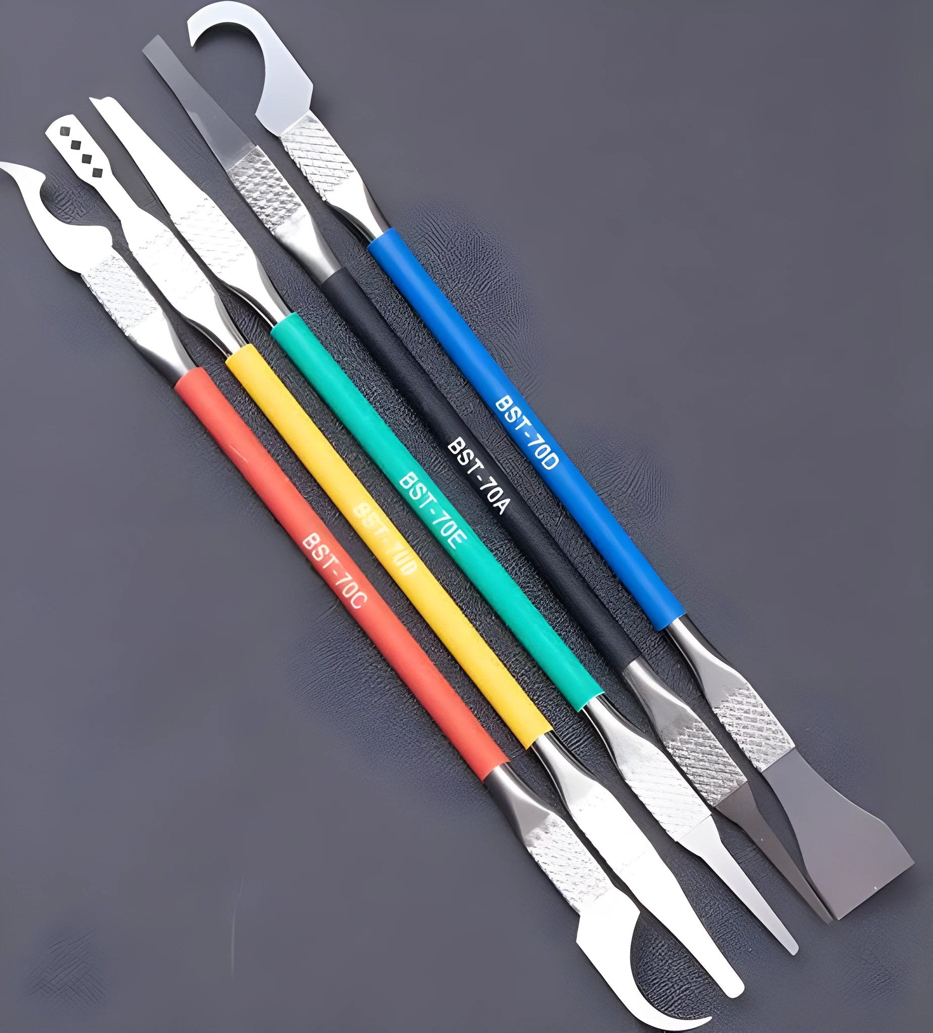 Five stainless steel plastic removal pry tools for electronics disassembly on a work surface.