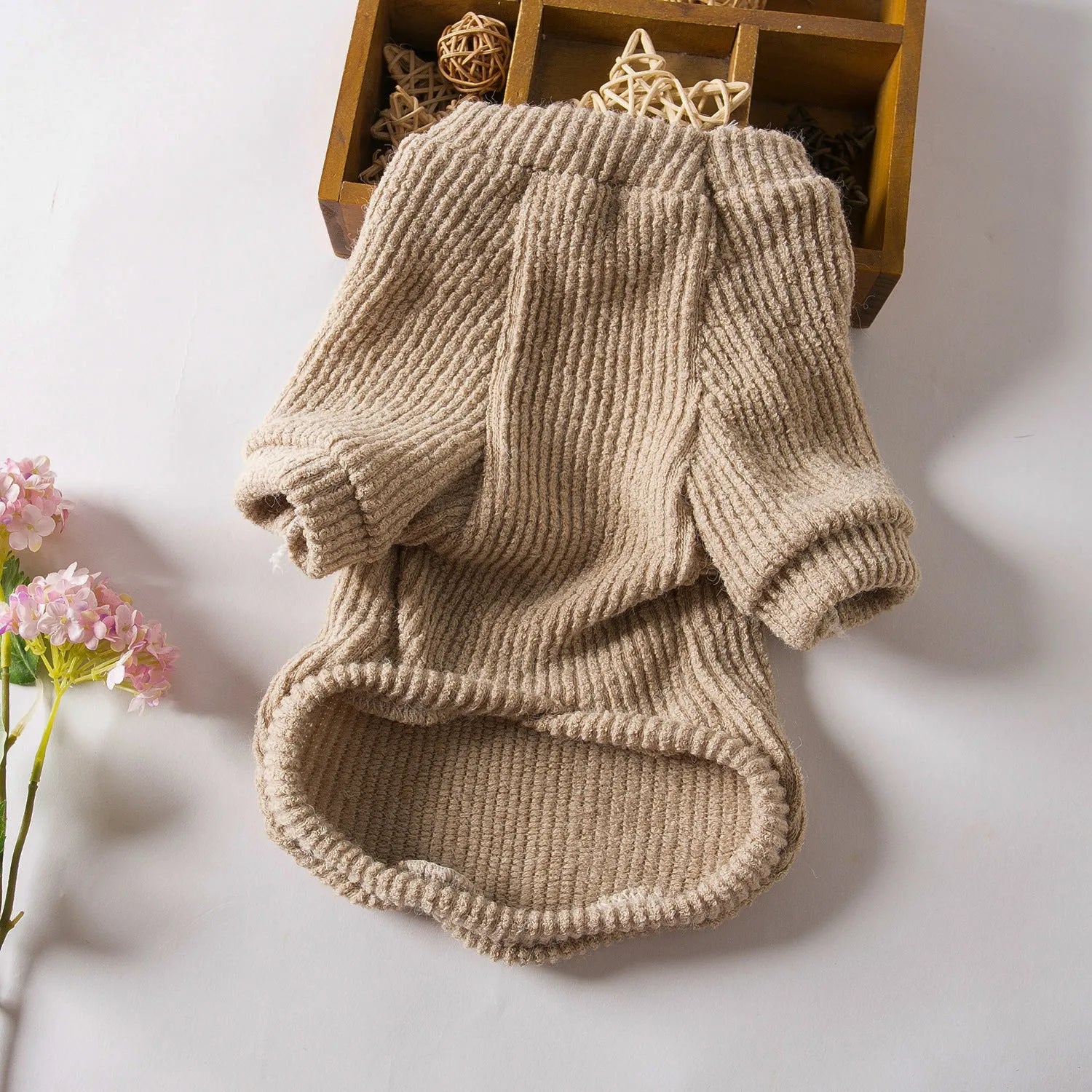 Brown knitted dog sweater on a small white dog, showing a casual pullover style.
