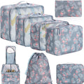 Eight cubic travel packing bags in various colours including beige, black, pink, leopard print, and striped patterns