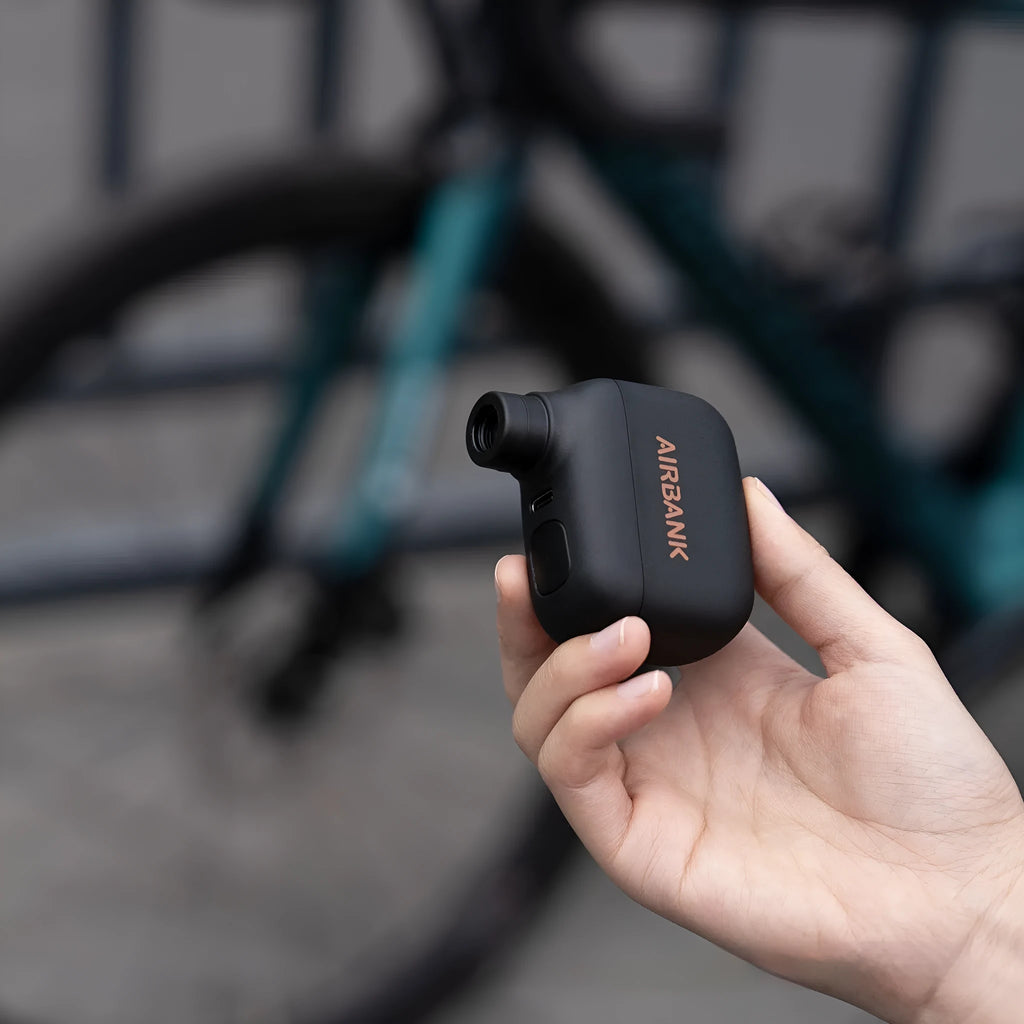 Black AS100 mini electric bicycle tyre pump with USB cable and waterproof storage bag.