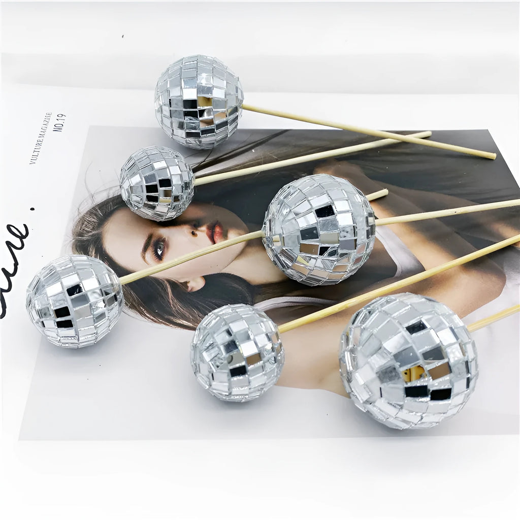 Glass disco ball cake decoration with wooden stick in various sizes on a cake.