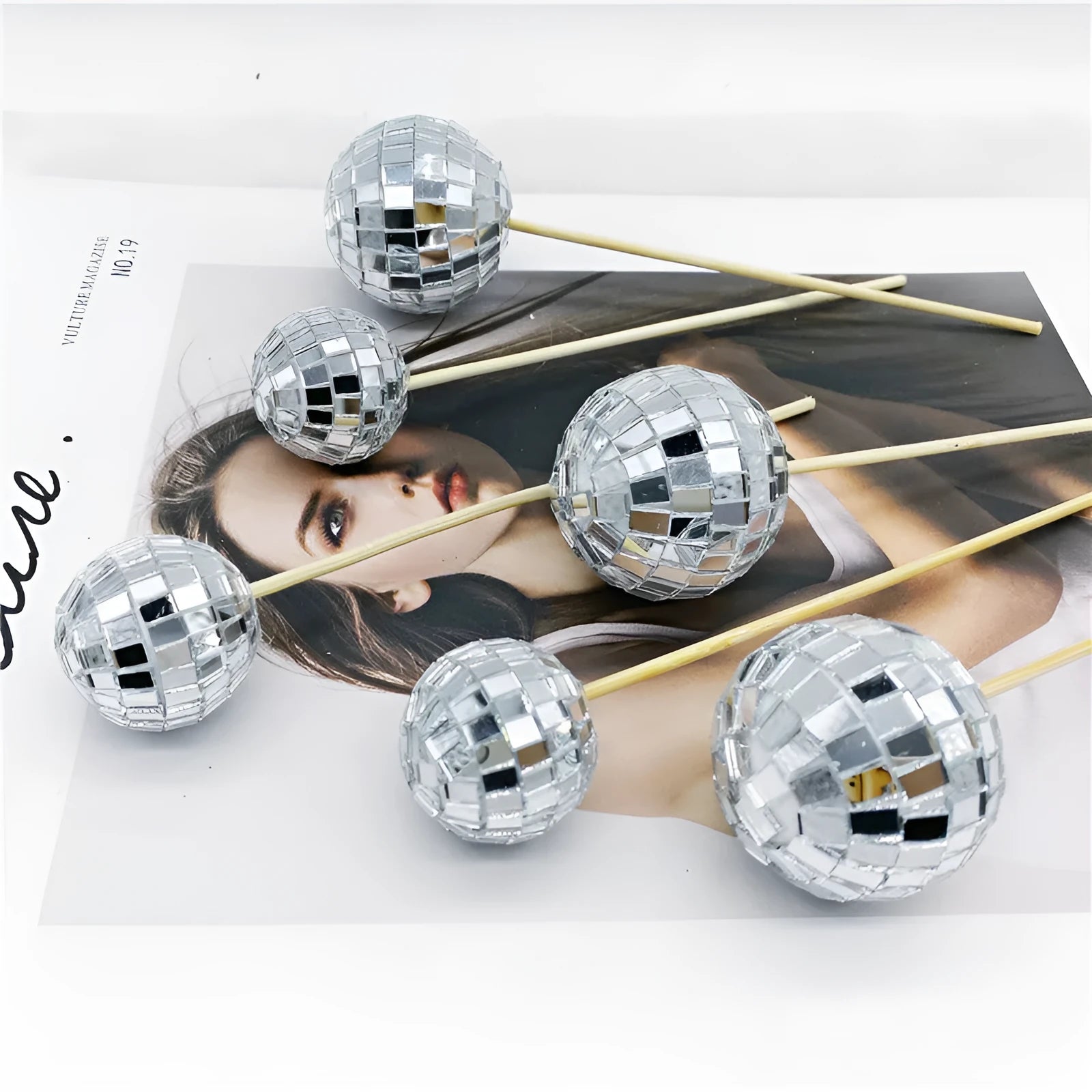 Glass disco ball cake decoration with wooden stick in various sizes on a cake.
