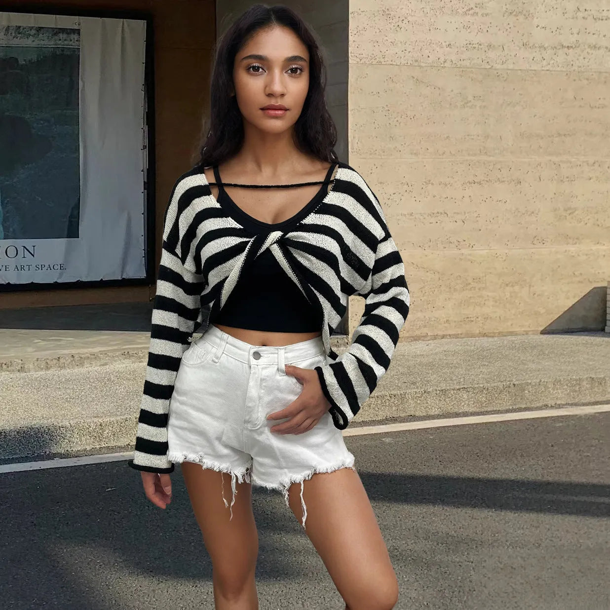 Woman wearing a striped cropped long-sleeved sweater in coloured cotton, showcasing the front and back wearable design.