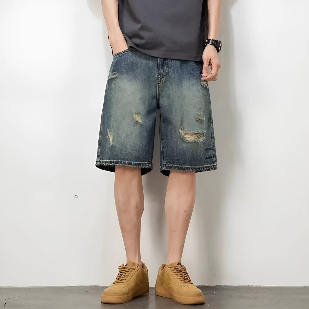Man wearing blue retro loose-hole denim shorts with a straight leg cut on a casual background.