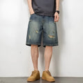Man wearing blue retro loose-hole denim shorts with a straight leg cut on a casual background.