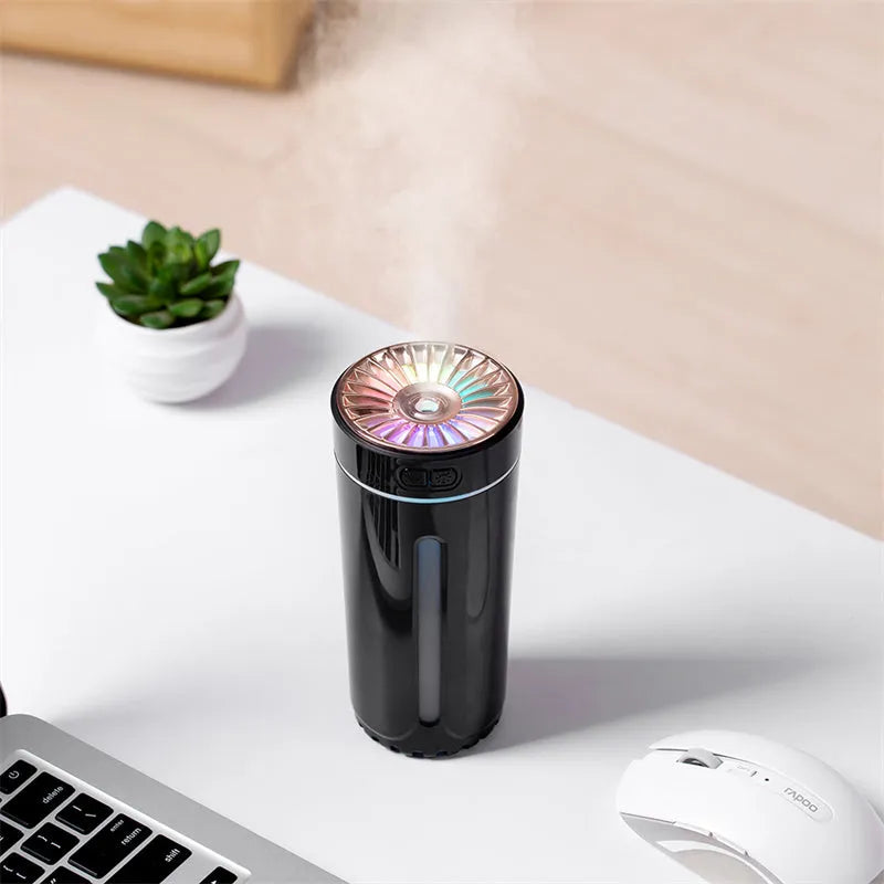 Compact black wireless humidifier with colourful LED lights sitting in car cup holder