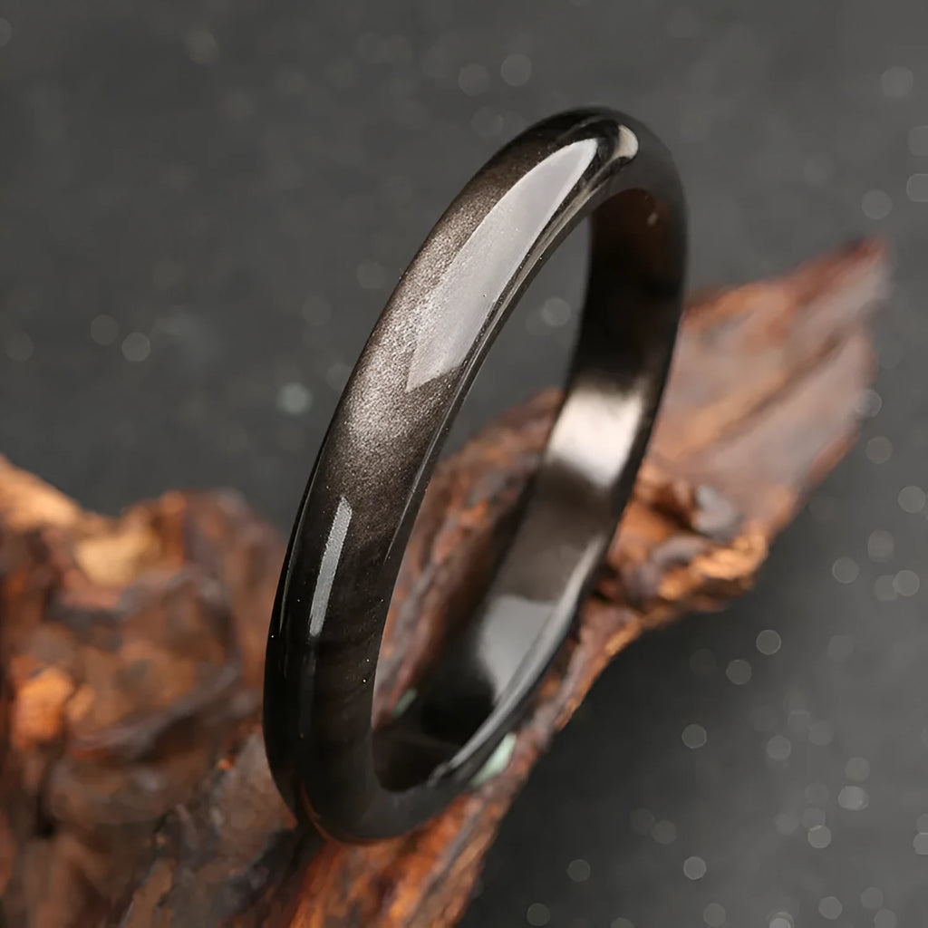 Obsidian cat's eye ethnic bracelet with geometric design on wrist, showing alloy and crystal construction.