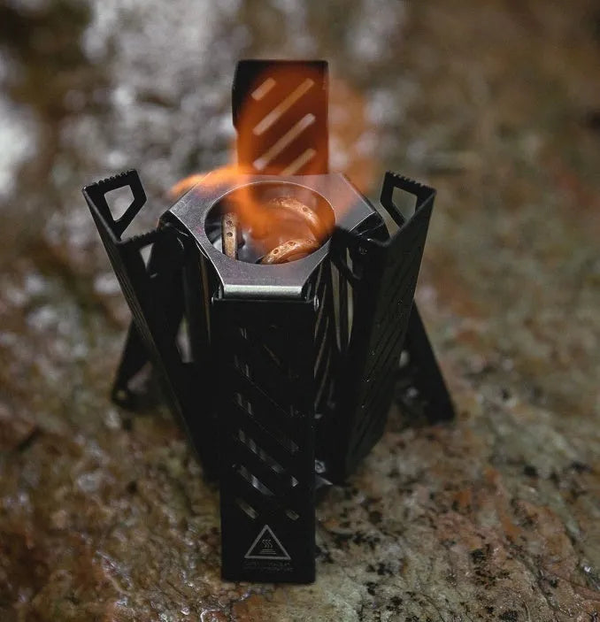 Black hexagon-shaped foldable alcohol camping stove shown next to a ruler showing its 15cm height