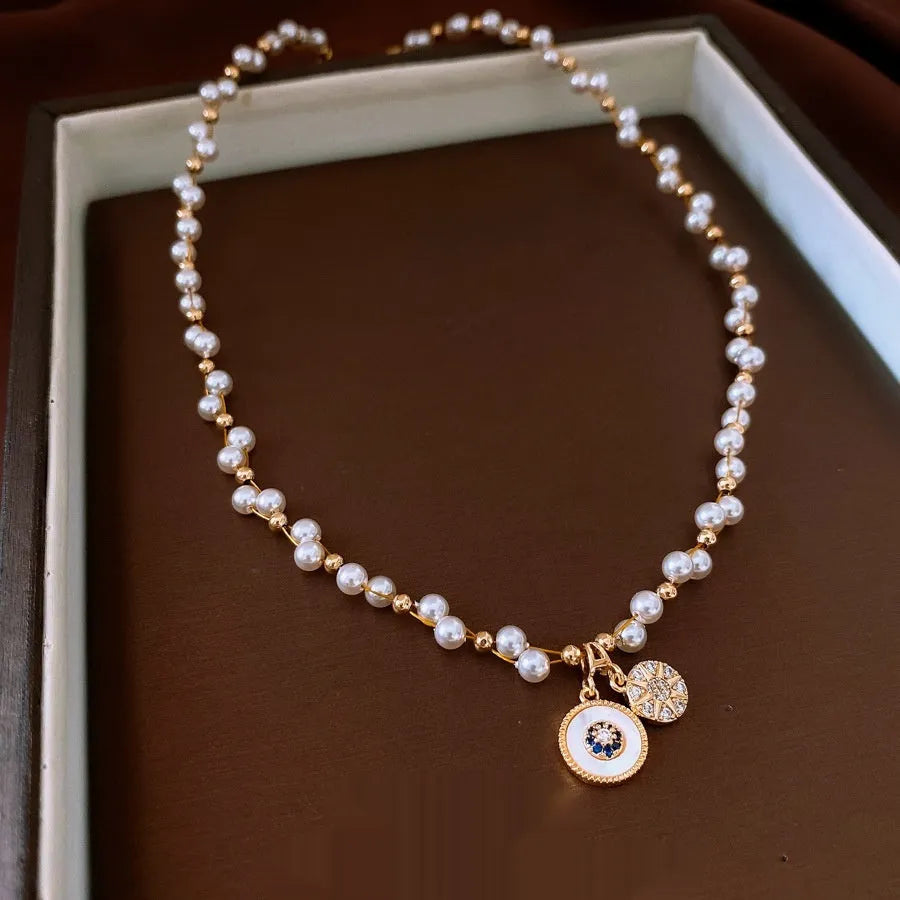 Gold electroplated necklace with zircon and imitation pearl pendant on an adjustable clavicle chain.