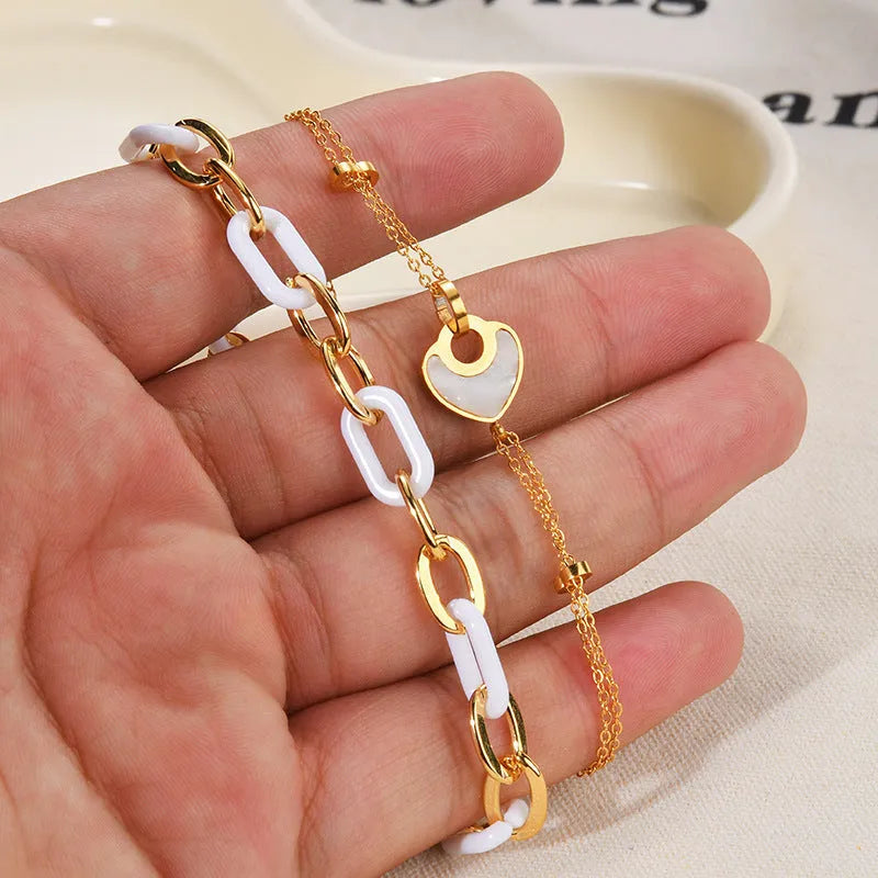 Women's stainless steel bracelet with double-layer design and a hanging heart charm in a resin-like electroplated finish.