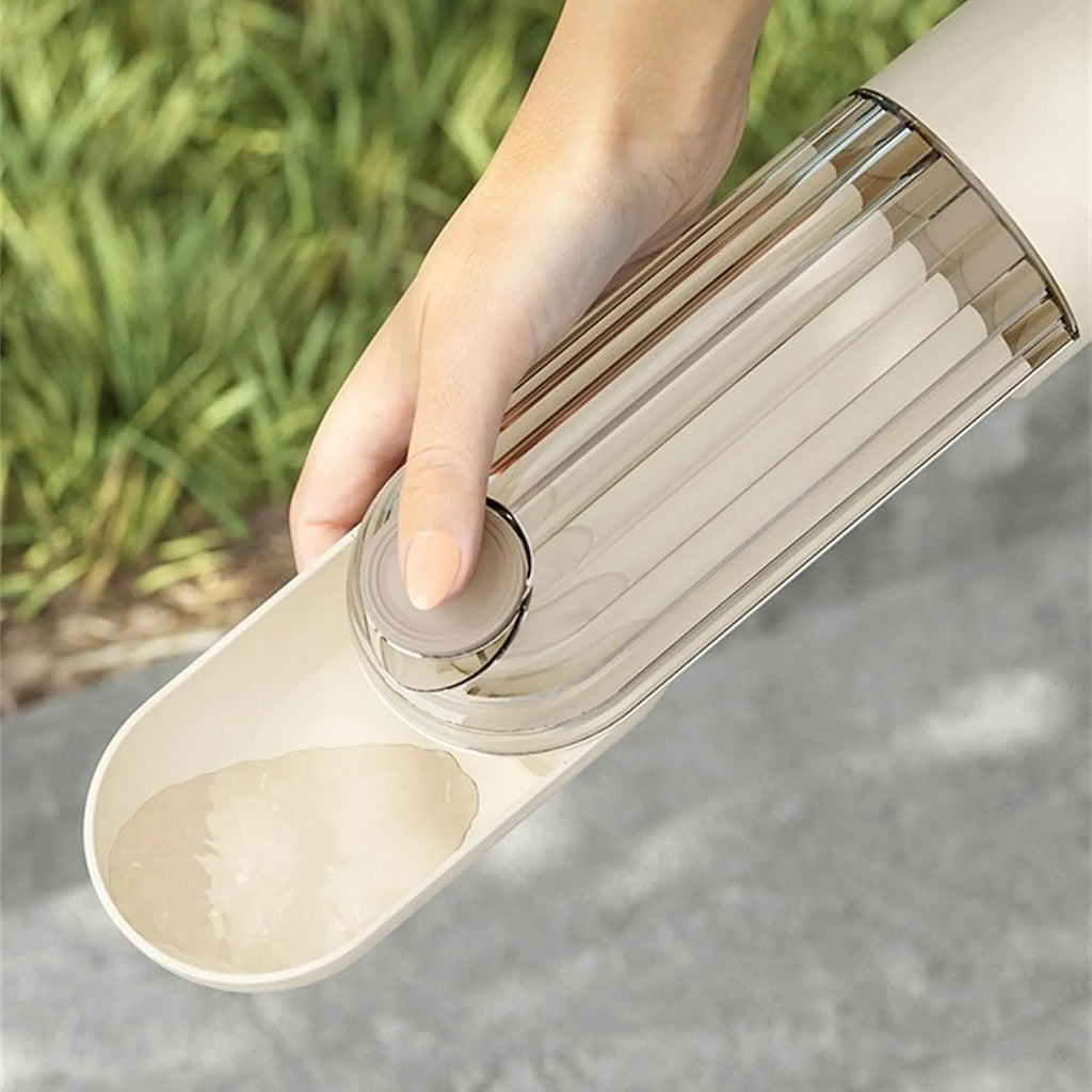 Foldable beige dog water bottle with food dispenser tray extended for drinking outdoors