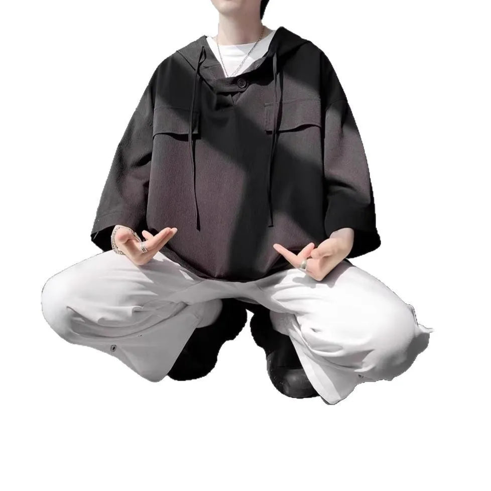 Man wearing a loose-fit black polyester hooded t-shirt with short sleeves.