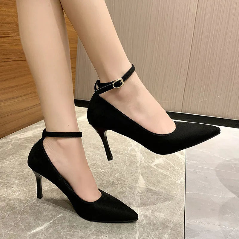 Black and creamy white women's stiletto heel pumps with a metal buckle detail on the upper.
