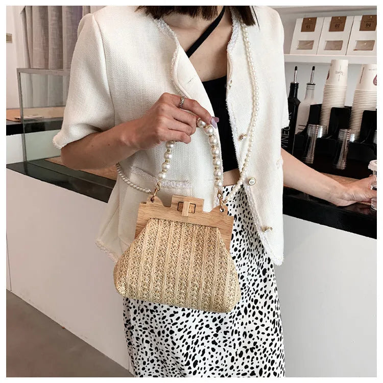 Women's woven straw shoulder bag with pearl chain strap and zippered interior pockets in beige, black, or khaki