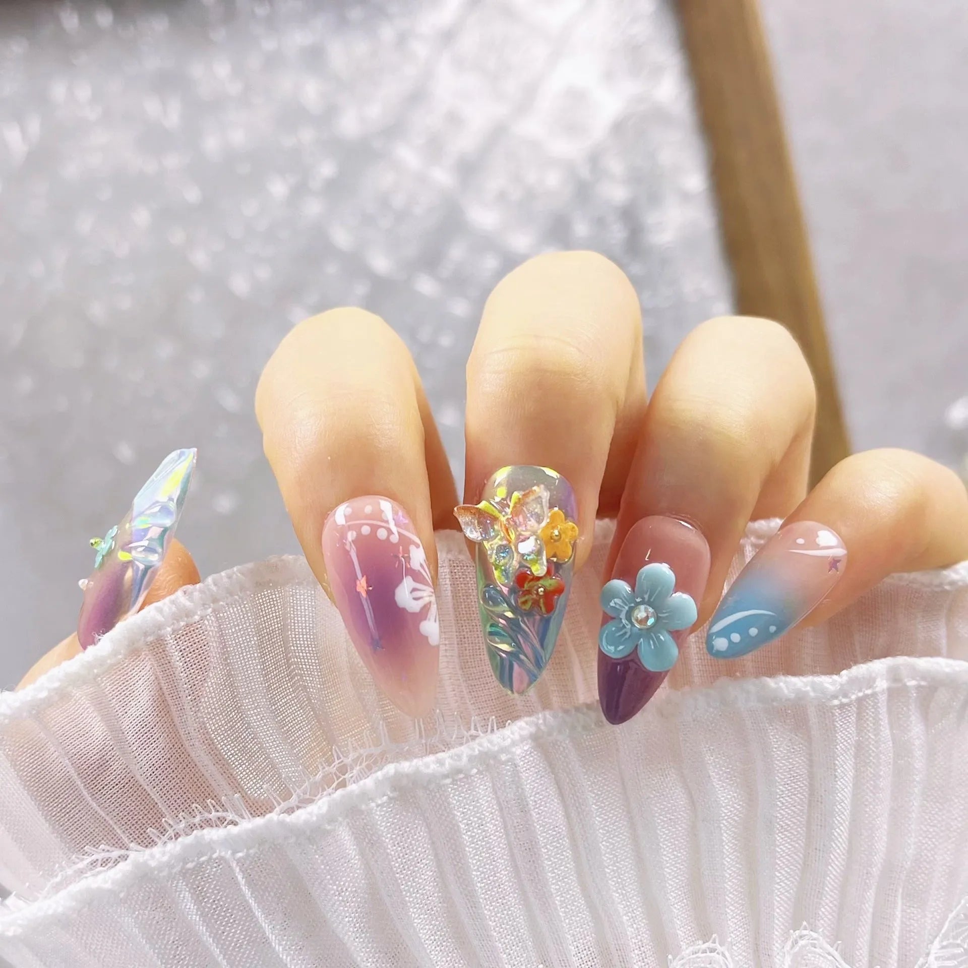 Handmade colourful false nails with embossed small flower and butterfly designs in almond shape.