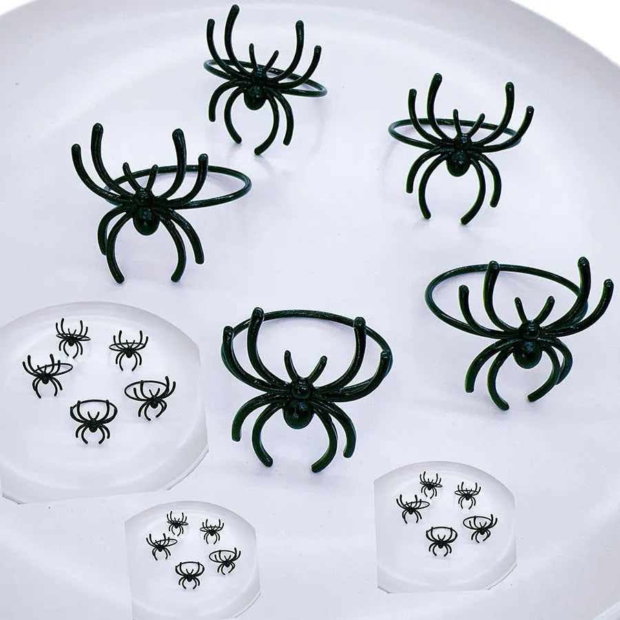 Six black alloy spider-shaped napkin rings for Halloween table settings.