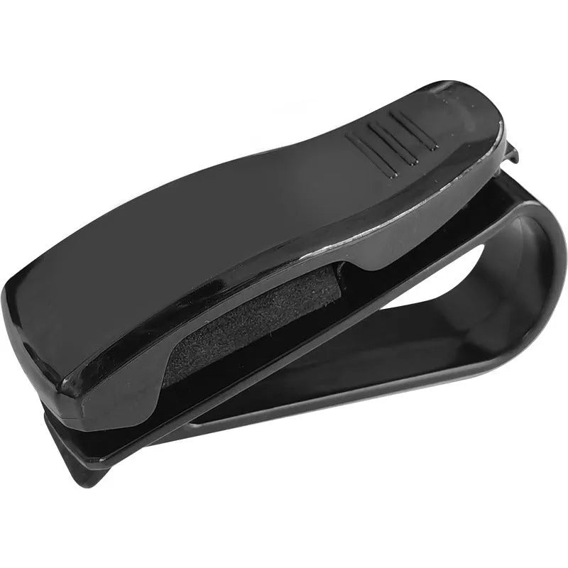 Black plastic multifunctional car mounted glasses and card clip attached to a sun visor holding sunglasses and an ID card