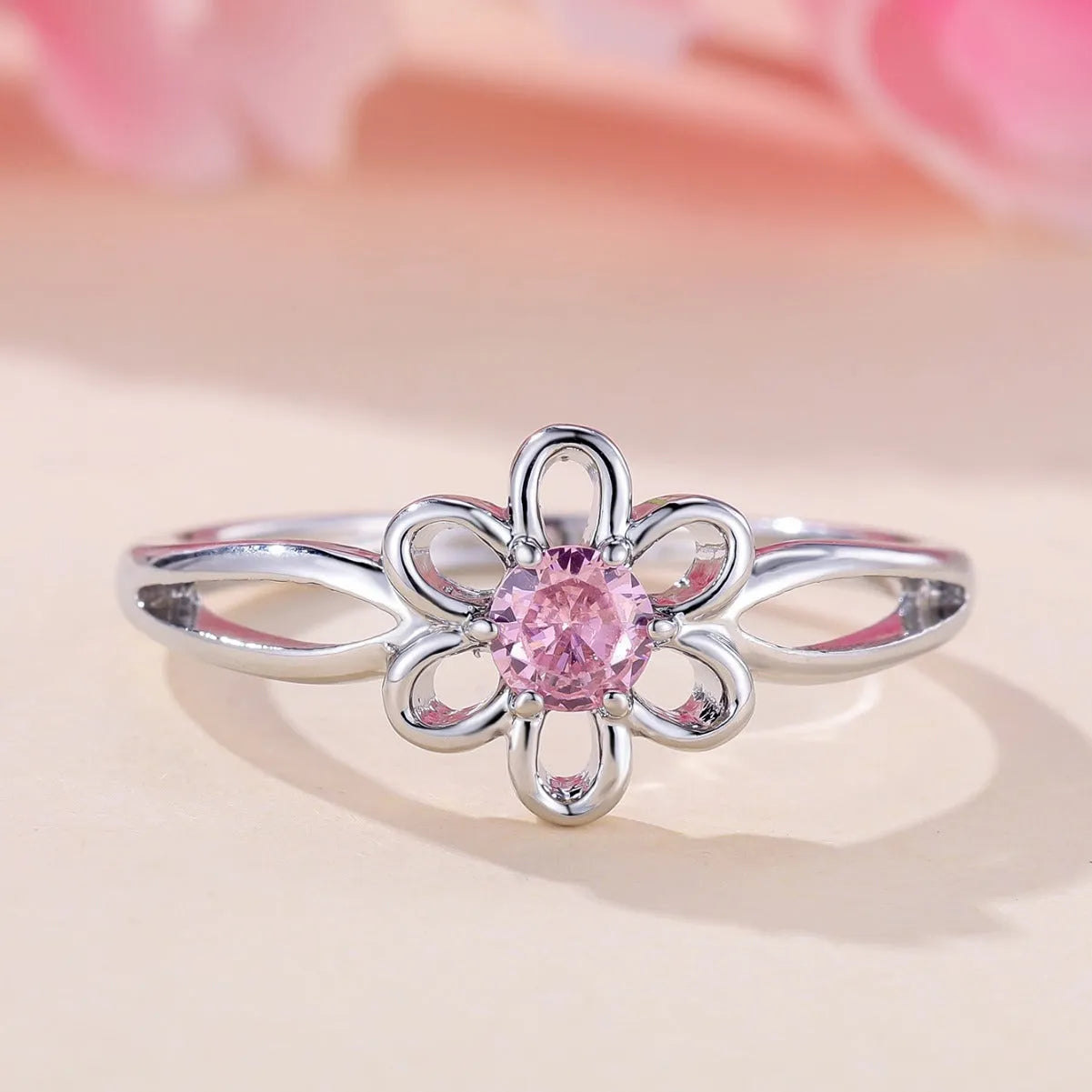 Close-up of a women's hollowed flower ring with a platinum pink diamond electroplated finish.