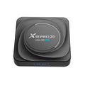 Compact black Android TV set-top box with remote control and HDMI cable on a wooden surface.