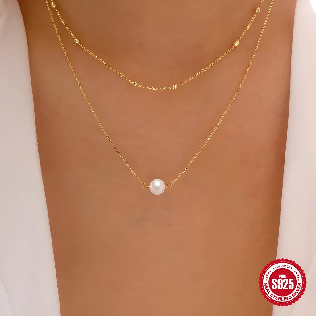 Close-up of a sterling silver double layer necklace with twin pearls on a ball bead chain, shown in gold tone.