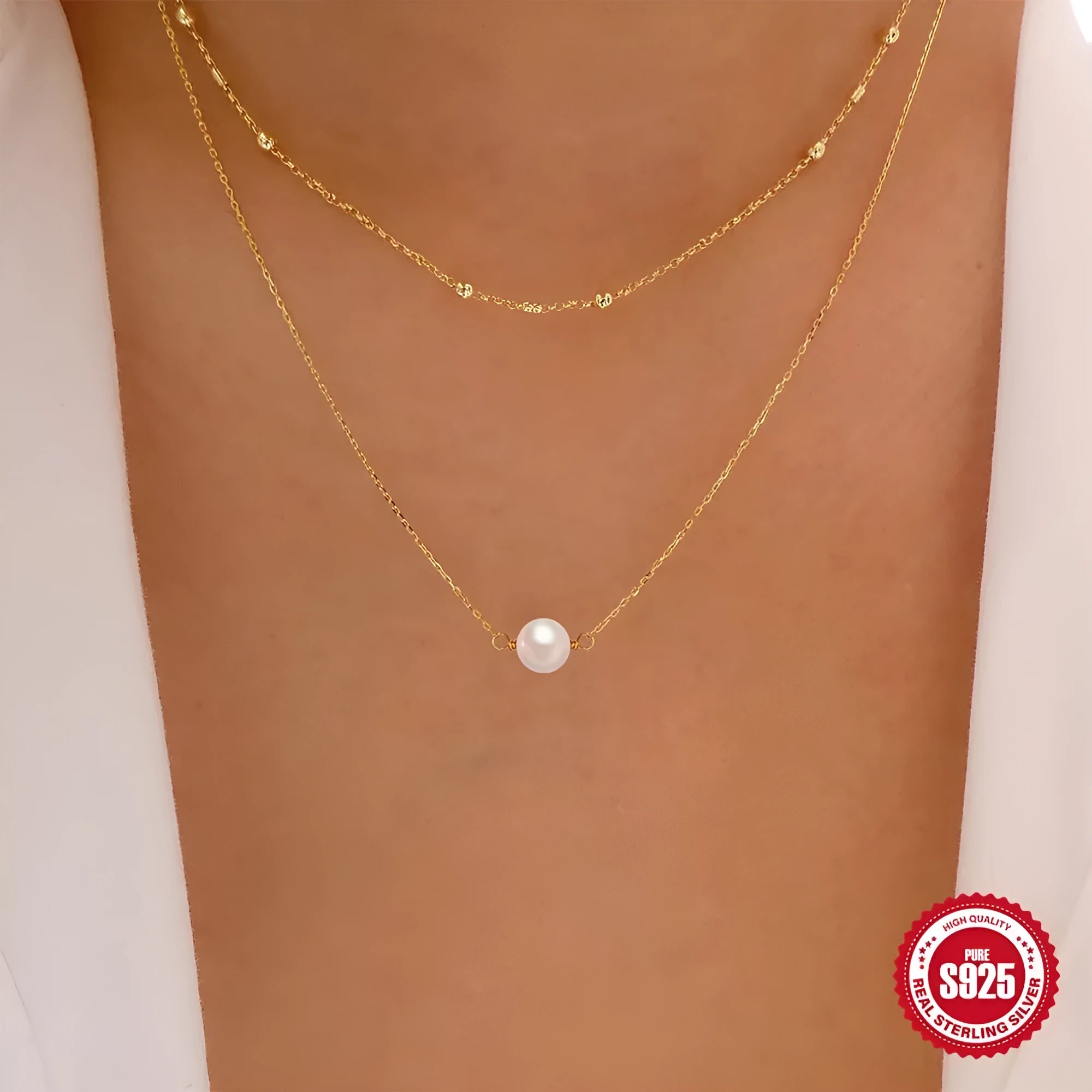 Close-up of a sterling silver double layer necklace with twin pearls on a ball bead chain, shown in gold tone.