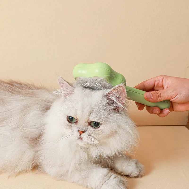 Green and yellow self-cleaning cat comb with stainless steel needles for pet grooming.