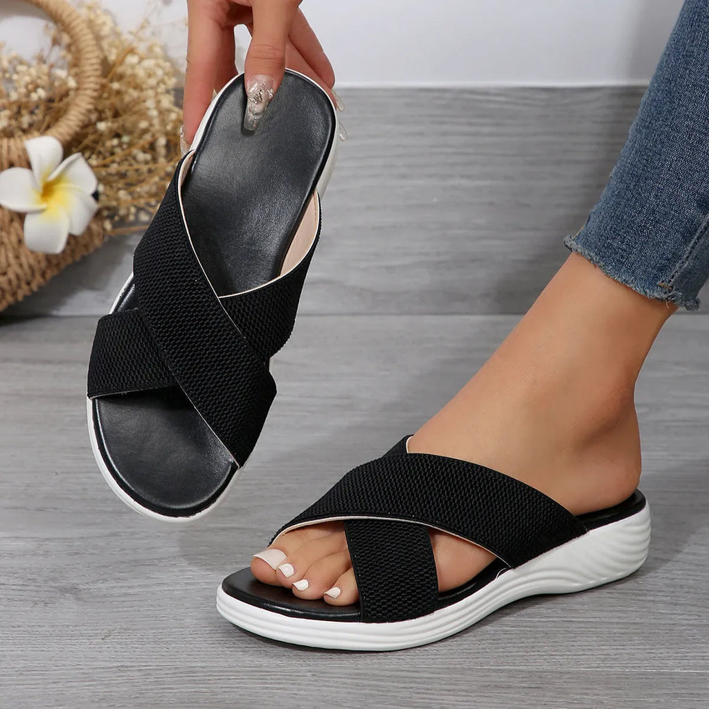 Black women's flat wedge peep-toe slippers with a thick rubber sole and PVC upper.
