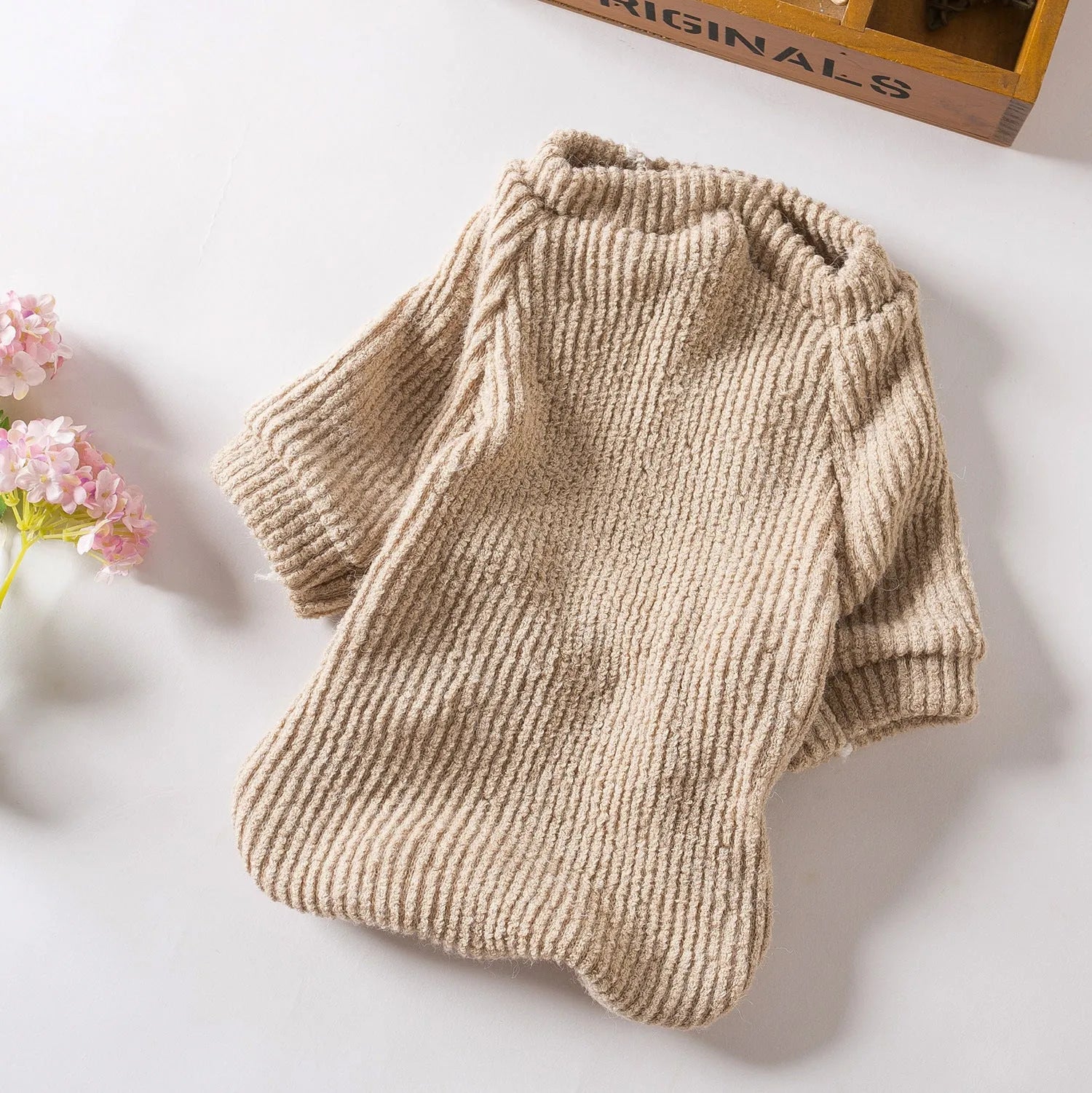 Brown knitted dog sweater on a small white dog, showing a casual pullover style.