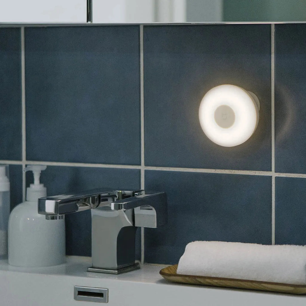 White square modern bedside table lamp with motion sensor and Bluetooth, shown on a nightstand.