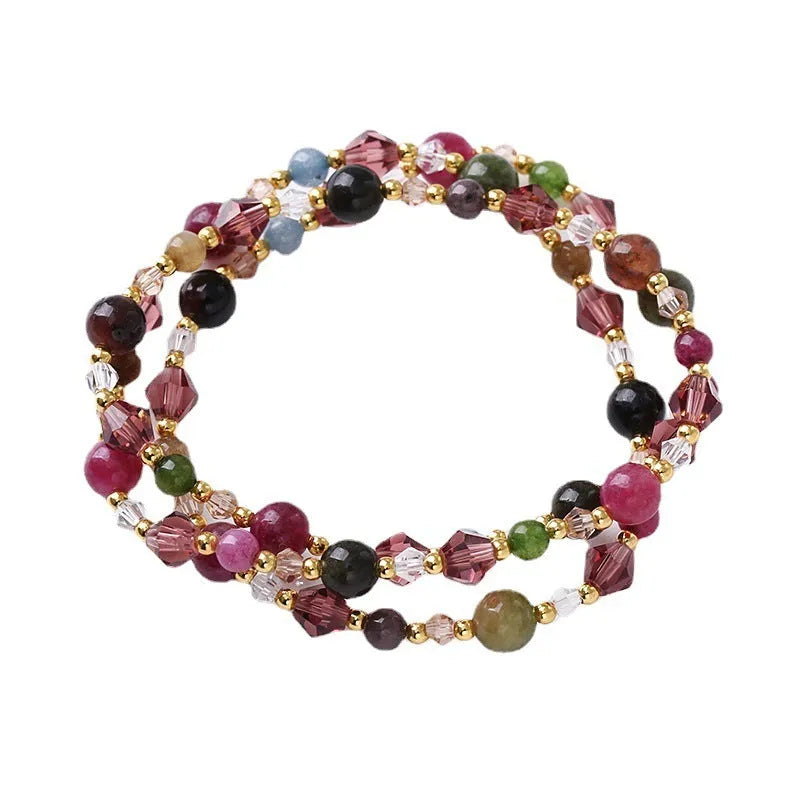 Women's handmade three-ring bracelet with tourmaline, strawberry quartz, and amethyst crystals on adjustable cord