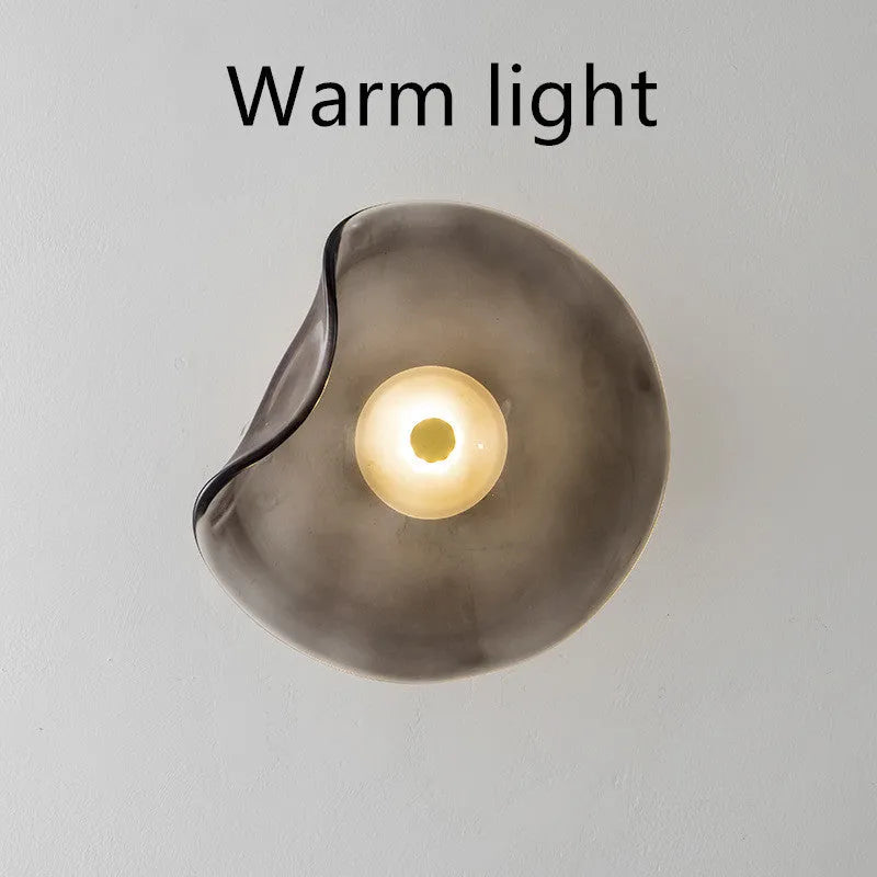 Round decorative wall lamp with glass shade in choice of cognac, light purple, or smoky grey finishes for bedroom lighting