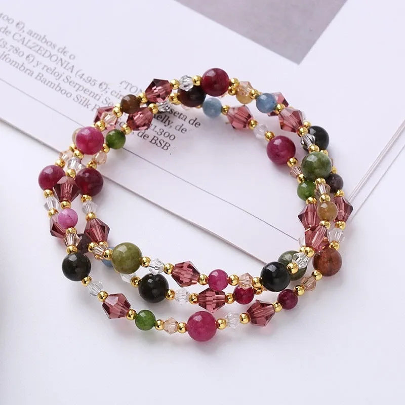 Women's handmade three-ring bracelet with tourmaline, strawberry quartz, and amethyst crystals on adjustable cord