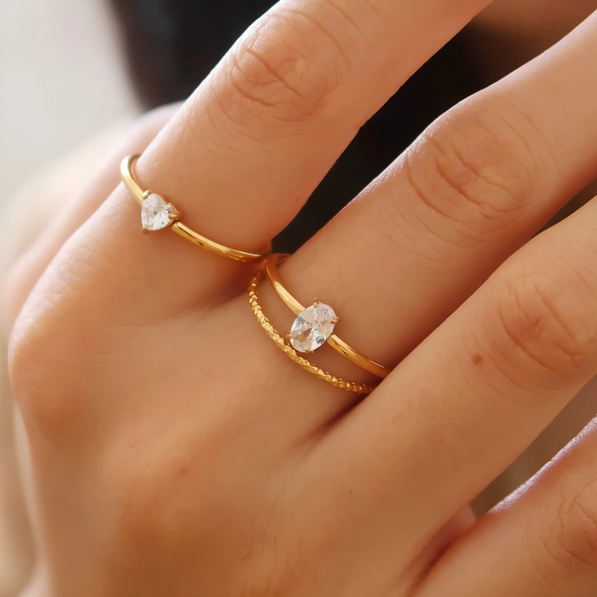 Gold electroplated stainless steel women's ring with heart design in oval shape on finger