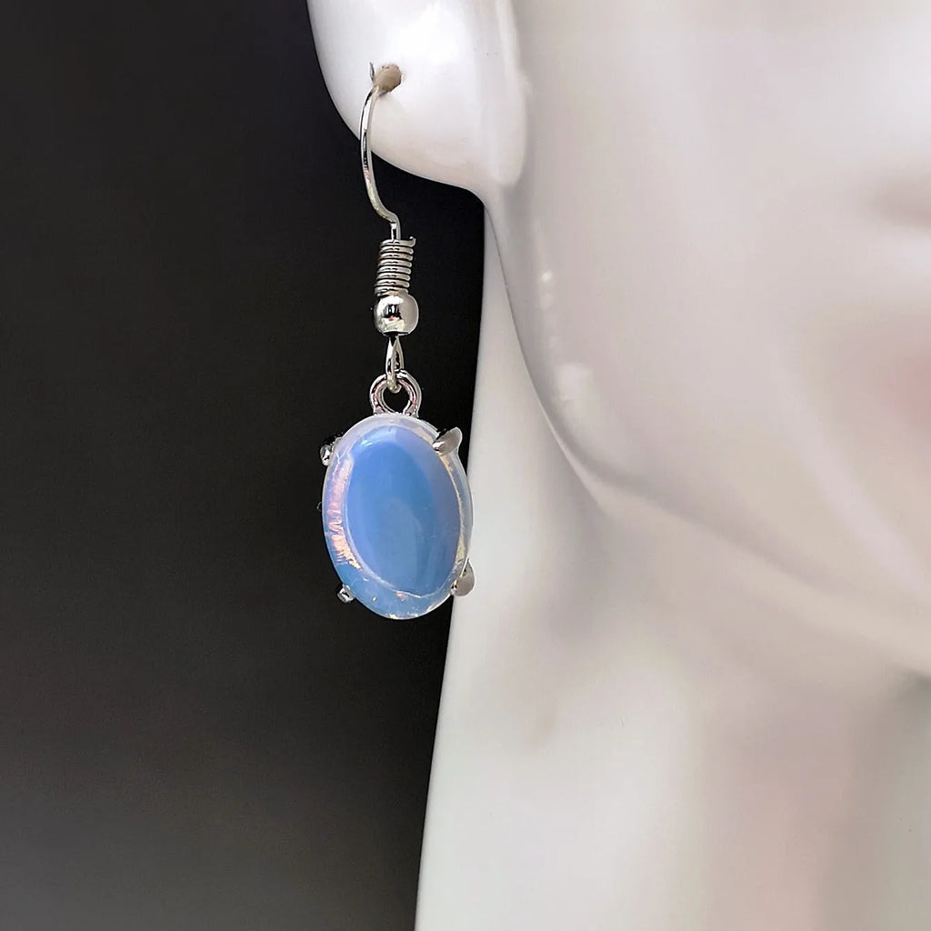 Pair of pale opal-colour drop earrings with a small cross detail on an elliptical alloy pendant.