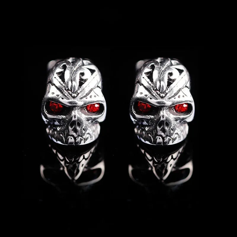 Pair of red eye skull stud earrings with alloy and gemstone inlay on a white background.