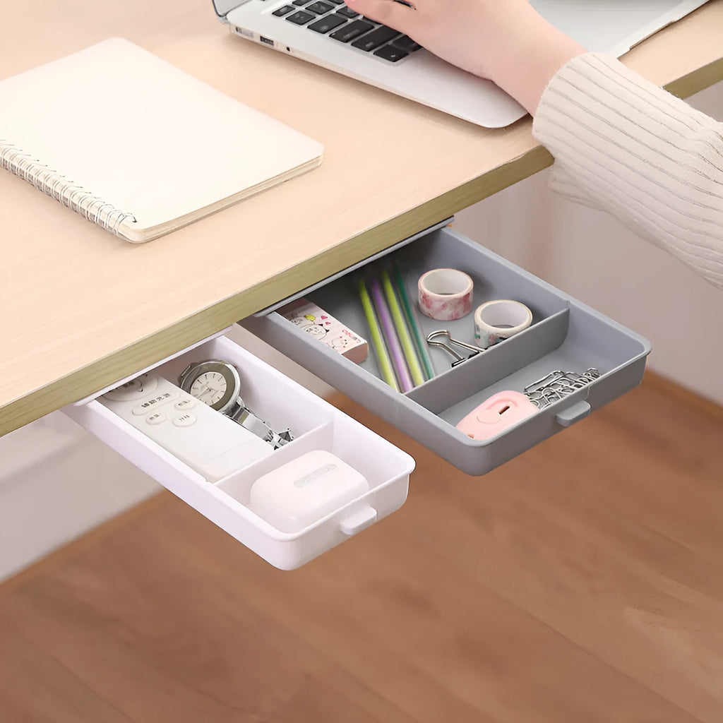 Small grey plastic drawer with a white cover and internal grid, shown mounted under a wooden table.