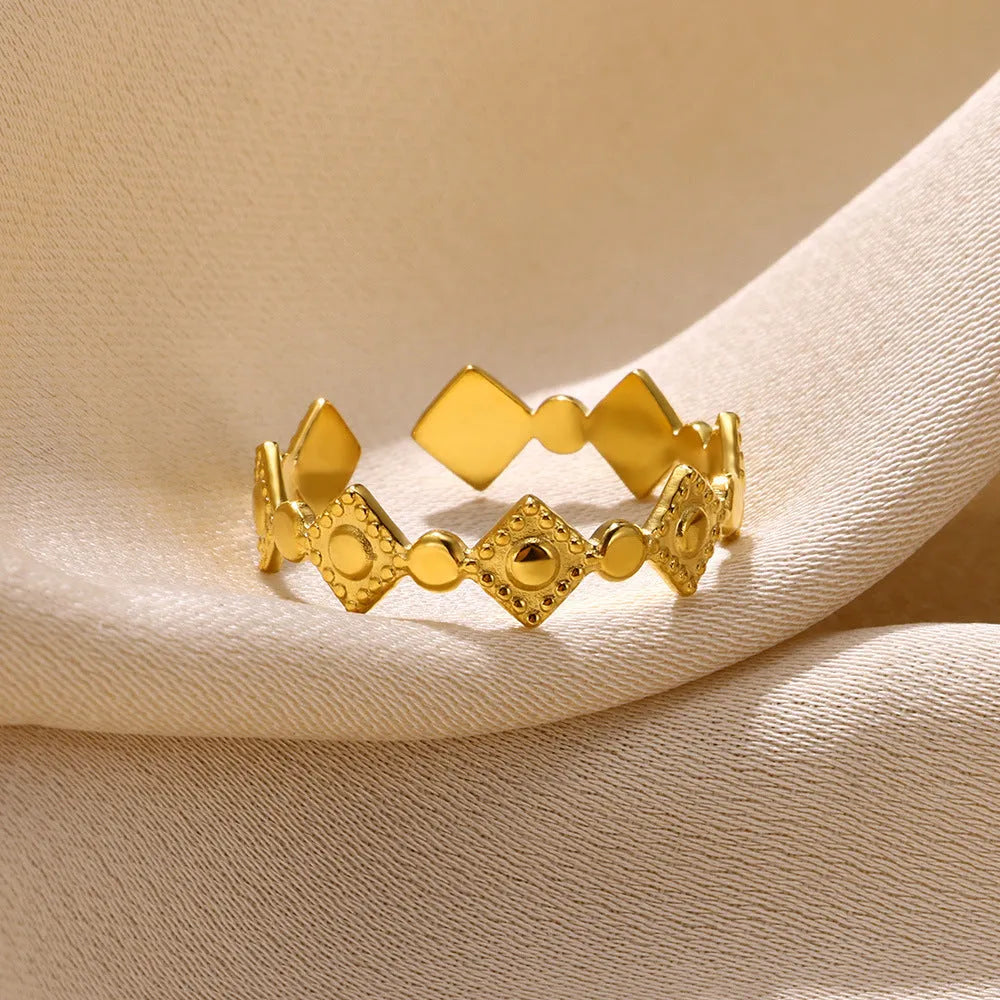 Gold diamond coloured geometric titanium steel ring for women on a flat surface.
