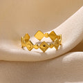 Gold diamond coloured geometric titanium steel ring for women on a flat surface.