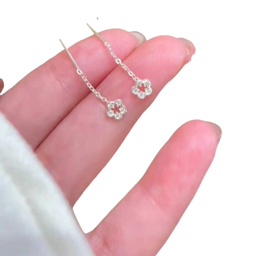 Silver-coloured alloy hollow flower hanging earrings with petal details on a white background.