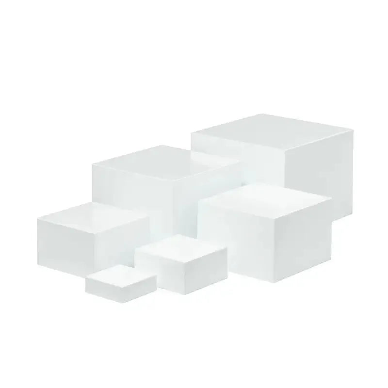 Set of six white plastic cube dessert display stands arranged on a table.