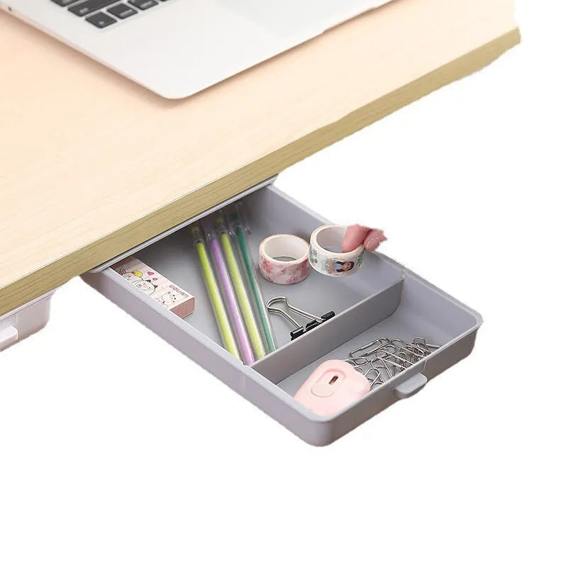 Small grey plastic drawer with a white cover and internal grid, shown mounted under a wooden table.
