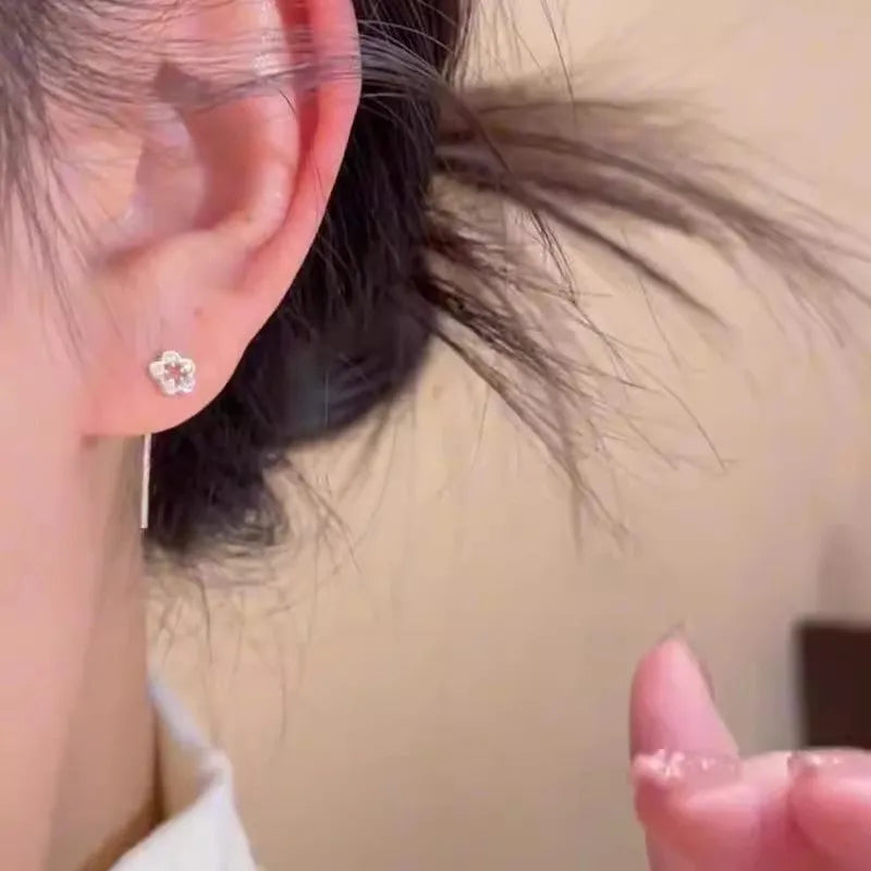 Silver-coloured alloy hollow flower hanging earrings with petal details on a white background.