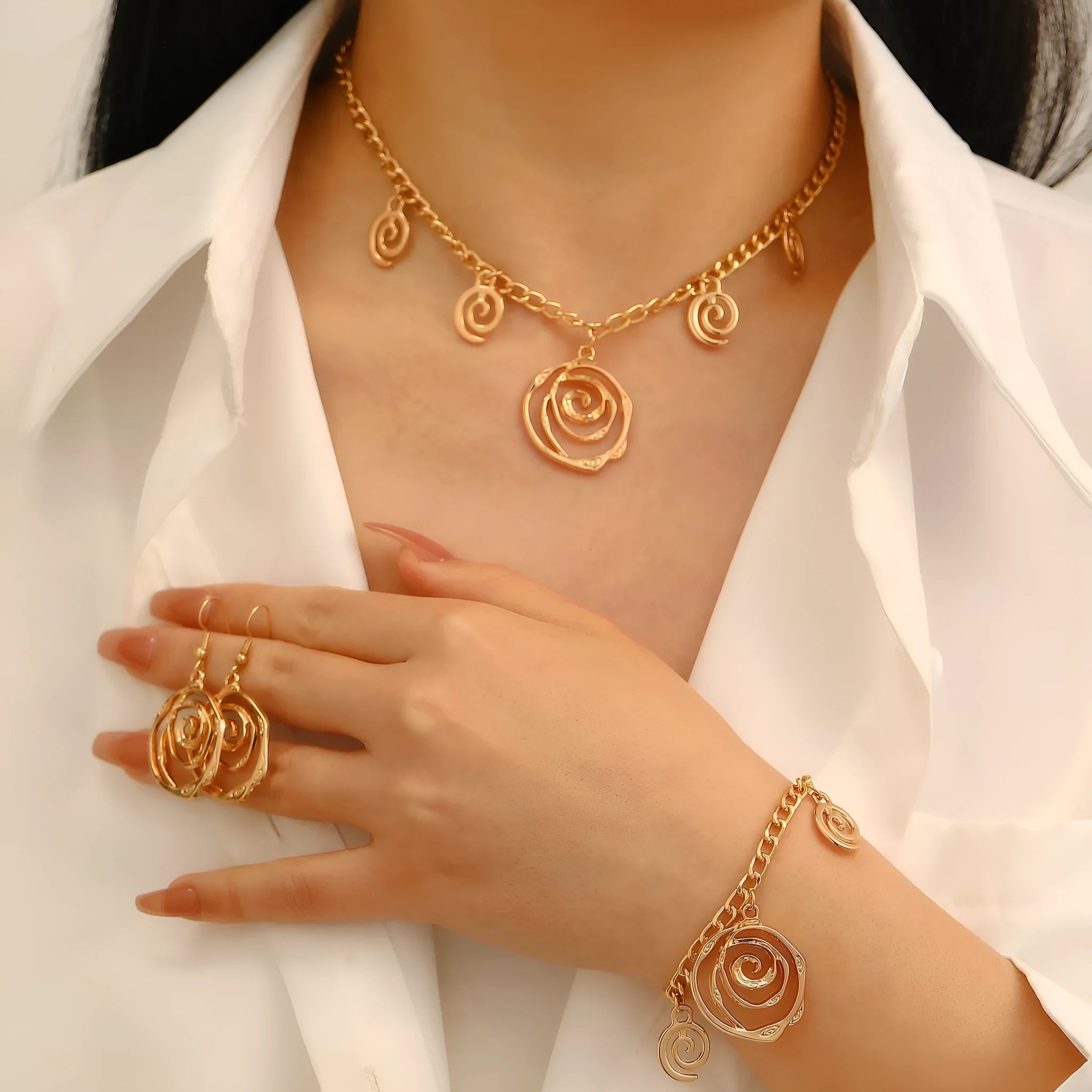 Gold spiral donut necklace, bracelet, and earrings set for women on a grey background.