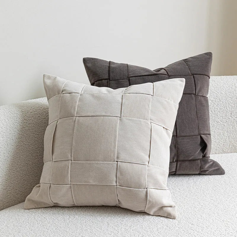 Square 50x50 cm chenille woven pillow cushion in beige colour on a grey sofa.