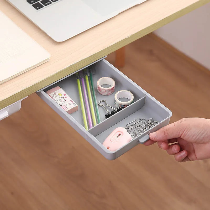 Small grey plastic drawer with a white cover and internal grid, shown mounted under a wooden table.